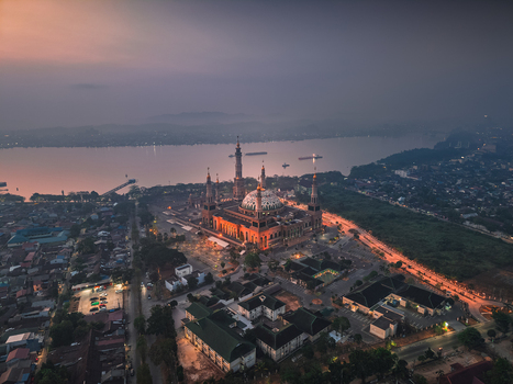 Aerial view of Baitul Muttaqien Mosque at the East Kalimantan Islamic Center illuminated at dusk by the Mahakam River in Samarinda East Kalimantan Indonesia.