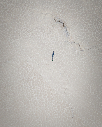 Aerial view of a person standing on the vast white salt crust of Salinas Grandes with intricate geometric patterns in La Poma Department Salta Province Argentina. Aerial view of a person standing on the vast white salt crust of Salinas Grandes with intricate geometric patterns in La Poma Department Salta Province Argentina.
