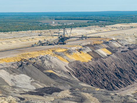 Aerial view of Tagebau Welzow Sud brown coal open pit mine featuring a large bucket wheel excavator layered soil strata and industrial landscape in Spremberg Brandenburg Germany. Aerial view of Tagebau Welzow Sud brown coal open pit mine featuring a large bucket wheel excavator layered soil strata and industrial landscape in Spremberg Brandenburg Germany.