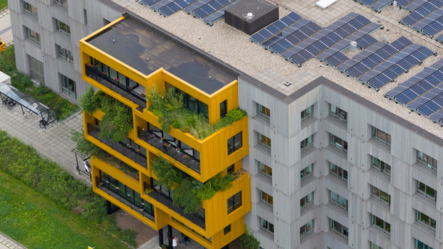 Aerial view of a modern apartment building featuring vibrant yellow balconies with lush greenery and solar panels on the rooftop in Almere Flevoland Netherlands. Aerial view of a modern apartment building featuring vibrant yellow balconies with lush greenery and solar panels on the rooftop in Almere Flevoland Netherlands.
