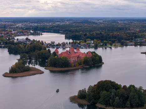 Aerial view of Trakai Island Castle featuring red brick towers and walls surrounded by the calm waters of Lake Galve and lush green trees in Trakai Vilniaus apskritis Lithuania.