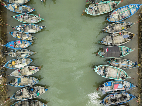 Aerial view of colorful boats clustered tightly in the Jepara Floating Fish Market their vibrant hulls contrasting with the murky green water Jepara Central Java Indonesia.