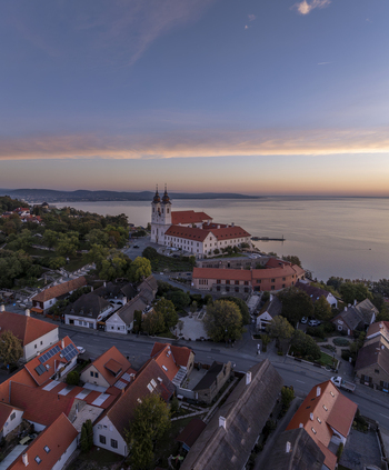 Aerial view of Tihany Abbey overlooking Lake Balaton at sunset with historic rooftops and lush greenery in Tihany Hungary. Aerial view of Tihany Abbey overlooking Lake Balaton at sunset with historic rooftops and lush greenery in Tihany Hungary.
