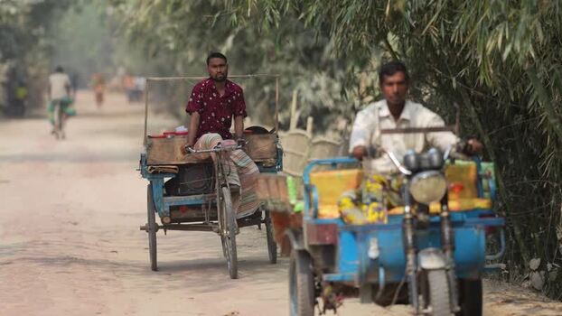 View of men driving cargo rickshaws on a rural road Bangladesh.