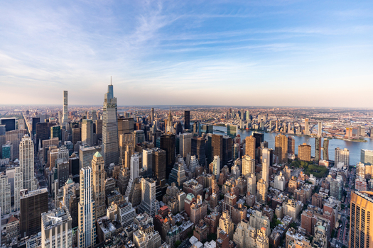 View of the dense Manhattan skyline with iconic skyscrapers glass towers and the East River under a clear blue sky in New York New York United States. View of the dense Manhattan skyline with iconic skyscrapers glass towers and the East River under a clear blue sky in New York New York United States.