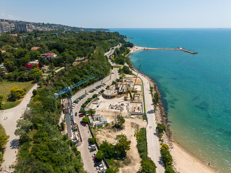 Aerial view of a construction site with a crane situated near the lush green trees of the Sea Garden and the Black Sea coastline in Varna Varna Bulgaria. Aerial view of a construction site with a crane situated near the lush green trees of the Sea Garden and the Black Sea coastline in Varna Varna Bulgaria.