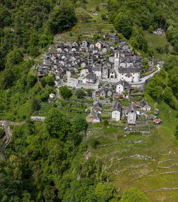 Aerial view of Corippo Albergo Diffuso and traditional stone houses nestled on a steep green hillside in the Verzasca Valley Corippo Ticino Switzerland. Aerial view of Corippo Albergo Diffuso and traditional stone houses nestled on a steep green hillside in the Verzasca Valley Corippo Ticino Switzerland.