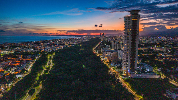 Aerial view of Caney Tower rising above the lush Mirador Sur Park with the city skyline and Caribbean Sea at sunset Santo Domingo Distrito Nacional Dominican Republic. Aerial view of Caney Tower rising above the lush Mirador Sur Park with the city skyline and Caribbean Sea at sunset Santo Domingo Distrito Nacional Dominican Republic.