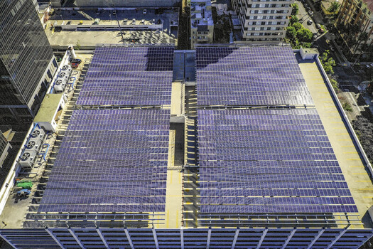 Aerial view of a large solar array system installed on a rooftop in an urban setting featuring multiple panels capturing sunlight in Los Angeles California United States. Aerial view of a large solar array system installed on a rooftop in an urban setting featuring multiple panels capturing sunlight in Los Angeles California United States.