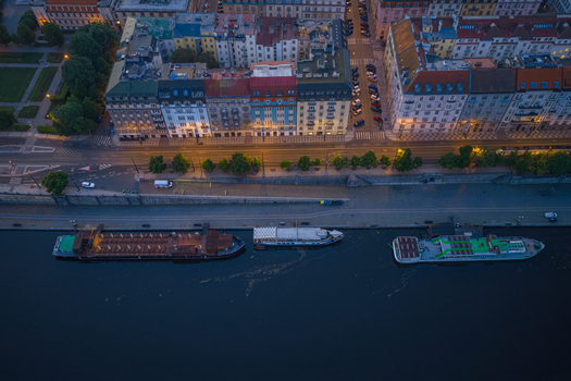 Aerial view of boats moored along the Vltava River embankment with historic buildings illuminated street lights and evening atmosphere in Prague Prague Czechia.