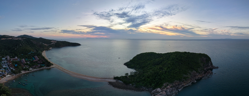 Aerial view of the sandbar connecting to Ko Pha Ngan island at sunset with calm sea lush tropical vegetation and colorful clouds in Ko Pha ngan District Surat Thani Thailand.