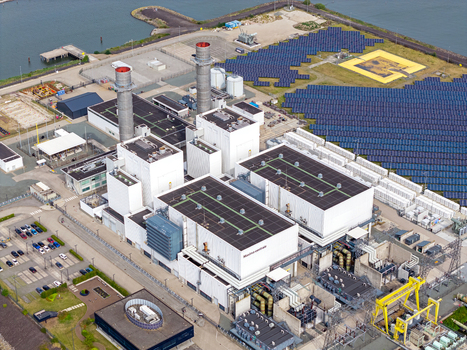 Aerial view of the Maxima power plant with its industrial buildings tall chimneys and extensive solar panel arrays located near the waterfront in Lelystad Flevoland Netherlands. Aerial view of the Maxima power plant with its industrial buildings tall chimneys and extensive solar panel arrays located near the waterfront in Lelystad Flevoland Netherlands.