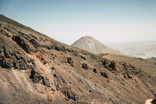 View of the volcanic slopes of Mount Ararat with rugged rocky terrain under a clear sky in Turkey.