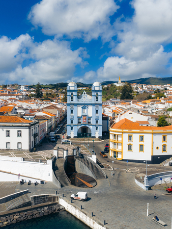 Aerial view of the blue Igreja da Misericordia overlooking the harbor square and historic orange roofed houses under a cloudy sky in Angra do Heroismo Azores Portugal.