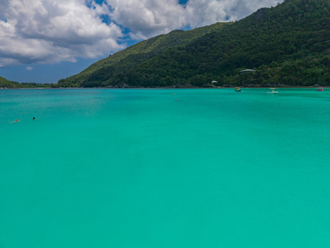 Aerial view of the turquoise waters meeting the lush green slopes of the island a scene of vibrant contrast and tranquil beauty Port Launay Mahe Island Seychelles. Aerial view of the turquoise waters meeting the lush green slopes of the island a scene of vibrant contrast and tranquil beauty Port Launay Mahe Island Seychelles.