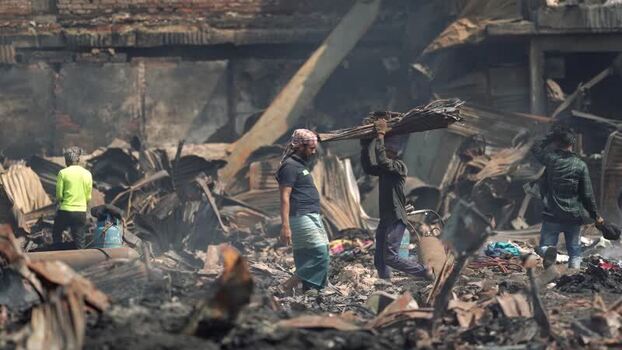 View of men walking through debris after a fire in Dhaka Bangladesh. View of men walking through debris after a fire in Dhaka Bangladesh.