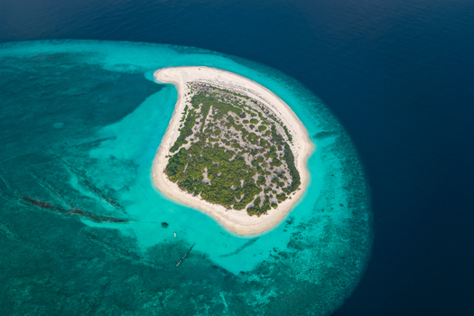 Aerial view of a small tropical island with lush green vegetation and white sandy beaches surrounded by turquoise coral reefs in Hoarafushi Haa Alif Atoll Maldives. Aerial view of a small tropical island with lush green vegetation and white sandy beaches surrounded by turquoise coral reefs in Hoarafushi Haa Alif Atoll Maldives.