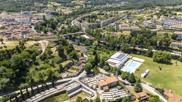 Aerial view of the historic town featuring a cemetery a swimming pool a river and surrounding lush green landscape in Allariz Province of Ourense Spain. Aerial view of the historic town featuring a cemetery a swimming pool a river and surrounding lush green landscape in Allariz Province of Ourense Spain.