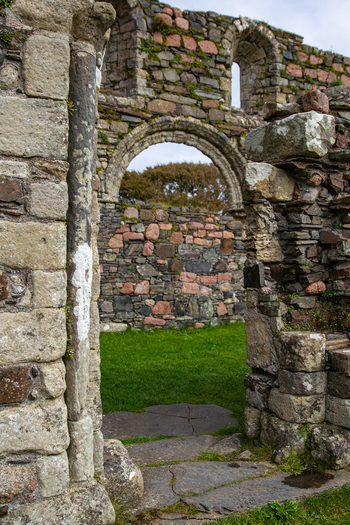 View of Iona Nunnery featuring ancient stone walls and a Romanesque arch overlooking green grass Baile Mor Scotland United Kingdom. View of Iona Nunnery featuring ancient stone walls and a Romanesque arch overlooking green grass Baile Mor Scotland United Kingdom.