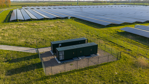 Aerial view of Solar park Delfzijl featuring rows of photovoltaic panels and green industrial containers on a grassy field in Farmsum Groningen Netherlands. Aerial view of Solar park Delfzijl featuring rows of photovoltaic panels and green industrial containers on a grassy field in Farmsum Groningen Netherlands.