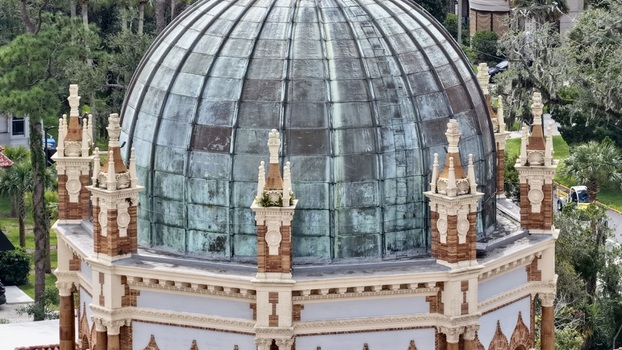 Aerial view of the ornate copper dome of Memorial Presbyterian Church surrounded by lush trees and historic architecture in St. Augustine Florida United States.