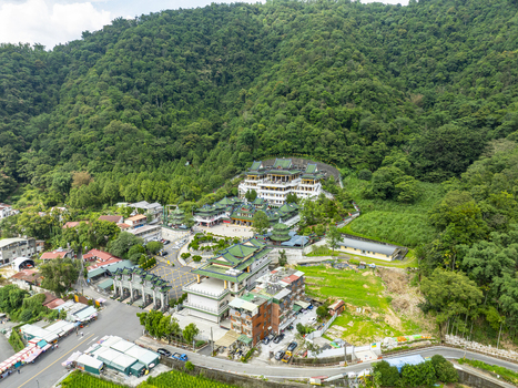 Aerial view of the Chung Tai Chan Monastery with its distinctive green tiled roofs and tiered architecture nestled against a lush forested mountain slope in Puli Township Nantou County Taiwan. Aerial view of the Chung Tai Chan Monastery with its distinctive green tiled roofs and tiered architecture nestled against a lush forested mountain slope in Puli Township Nantou County Taiwan.