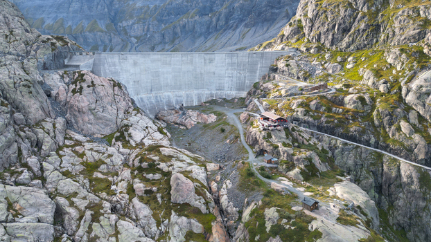 Aerial view of the Vieux Emosson dam nestled within the rugged rocky terrain of the Swiss Alps featuring a mountain hut and winding trails in Finhaut Valais Switzerland. Aerial view of the Vieux Emosson dam nestled within the rugged rocky terrain of the Swiss Alps featuring a mountain hut and winding trails in Finhaut Valais Switzerland.