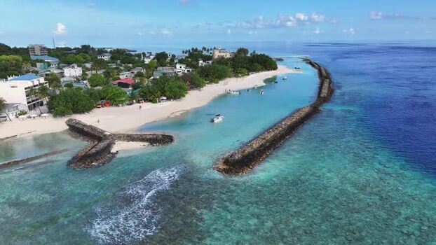 Aerial view of Thulusdhoo island beach and breakwaters Maldives.