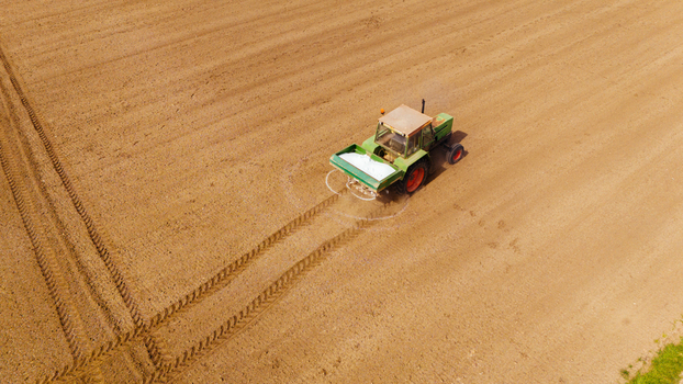 Aerial view of a tractor spreading fertilizer across the field leaving tire tracks on the soil Sremska Mitrovica Vojvodina Serbia. Aerial view of a tractor spreading fertilizer across the field leaving tire tracks on the soil Sremska Mitrovica Vojvodina Serbia.