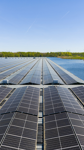 Aerial view of floating solar panels on a lake with green trees and a clear blue sky in Zwolle Overijssel Netherlands. Aerial view of floating solar panels on a lake with green trees and a clear blue sky in Zwolle Overijssel Netherlands.