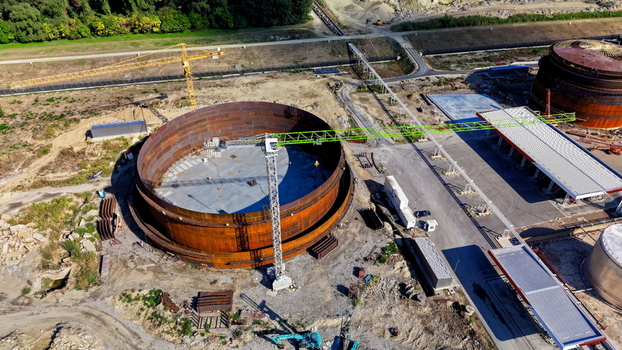 Aerial view of the assembly of a large circular fuel tank at an industrial refinery site with a construction crane and surrounding infrastructure in Kovin Vojvodina Serbia. Aerial view of the assembly of a large circular fuel tank at an industrial refinery site with a construction crane and surrounding infrastructure in Kovin Vojvodina Serbia.