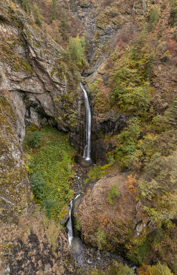 Aerial view of Ovcharenski Waterfall Goritsa cascading down rocky cliffs surrounded by autumn foliage in Ovchartsi Kyustendil Province Bulgaria. Aerial view of Ovcharenski Waterfall Goritsa cascading down rocky cliffs surrounded by autumn foliage in Ovchartsi Kyustendil Province Bulgaria.