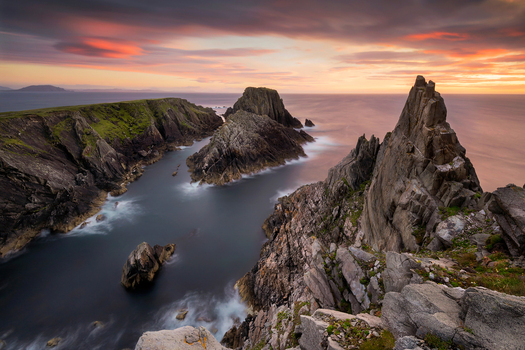 View of jagged rock formations and steep cliffs at the edge of the Atlantic Ocean under a sunset sky at Malin Head County Donegal Ireland.