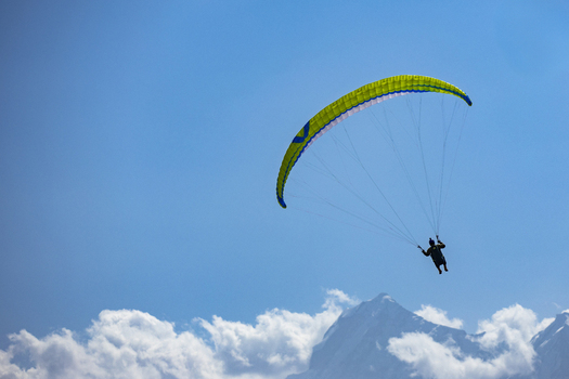 View of a paraglider soaring through the clear blue sky above the mountains of Booni Khyber Pakhtunkhwa Pakistan.