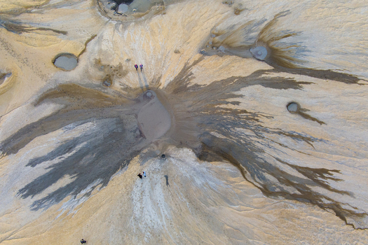 Aerial view of the Vulcanii Noroiosi Paclele Mari mud volcanoes featuring unique geological formations dried mud patterns and craters with people walking in Paclele Buzau County Romania.