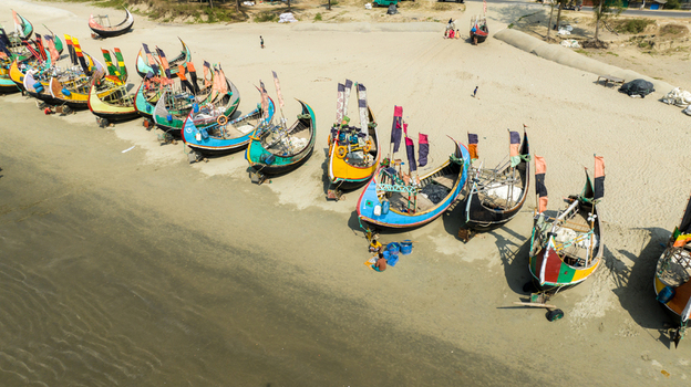Aerial view of vibrant fishing boats resting on the sandy shore their colorful hulls contrasting with the neutral beach Cox s Bazar Chittagong Division Bangladesh. Aerial view of vibrant fishing boats resting on the sandy shore their colorful hulls contrasting with the neutral beach Cox s Bazar Chittagong Division Bangladesh.