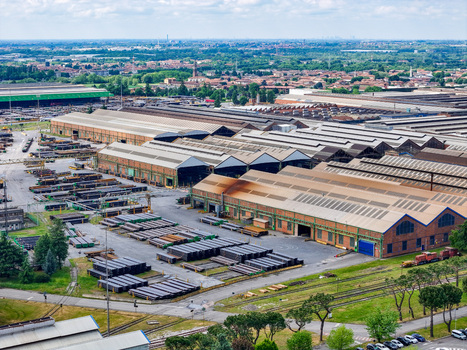 Aerial view of the vast industrial steel plant with large warehouses and stacks of metal pipes under a cloudy sky in Dalmine Lombardy Italy. Aerial view of the vast industrial steel plant with large warehouses and stacks of metal pipes under a cloudy sky in Dalmine Lombardy Italy.