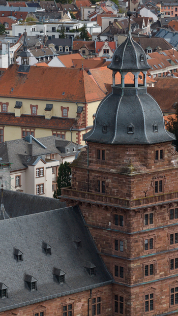 Aerial view of Schloss Johannisburg a historic red sandstone castle with a prominent tower and slate roof overlooking the urban rooftops of Aschaffenburg Bayern Germany.