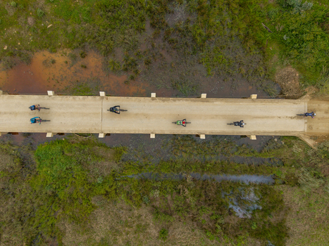 Aerial view of mountain bikers riding across a concrete bridge over marshy terrain in Greyton Western Cape South Africa.