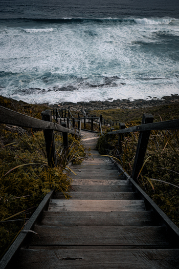 View of the wooden staircase leading down to the rocky coastline and crashing waves at Sandpatch Western Australia Australia. View of the wooden staircase leading down to the rocky coastline and crashing waves at Sandpatch Western Australia Australia.