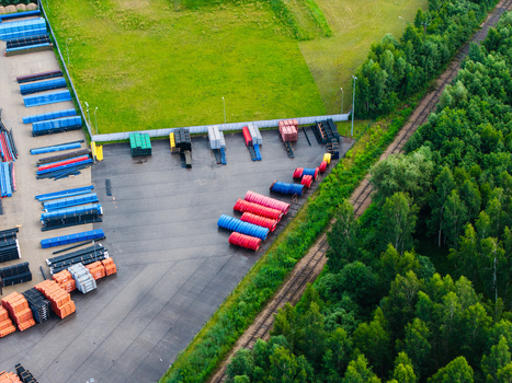 Aerial view of a storage yard filled with organized rows of colorful industrial polymer pipes situated next to a dense forest and railway tracks in Jelgava Latvia. Aerial view of a storage yard filled with organized rows of colorful industrial polymer pipes situated next to a dense forest and railway tracks in Jelgava Latvia.