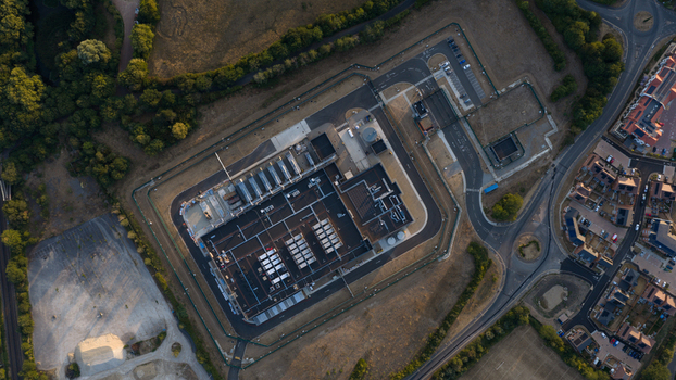 Aerial view of a large industrial facility with a fenced perimeter parking lot and surrounding residential area in Bracknell England United Kingdom.