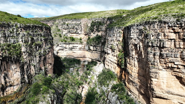 Aerial view of the dramatic El Vergel canyon featuring steep layered rock walls lush green vegetation at the base and rugged geological formations in Torotoro Potosi Department Bolivia. Aerial view of the dramatic El Vergel canyon featuring steep layered rock walls lush green vegetation at the base and rugged geological formations in Torotoro Potosi Department Bolivia.