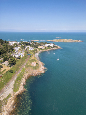 Aerial view of the Dalkey coastline featuring the railway line residential houses and Dalkey Island in the Irish Sea Dublin County Dublin Ireland. Aerial view of the Dalkey coastline featuring the railway line residential houses and Dalkey Island in the Irish Sea Dublin County Dublin Ireland.
