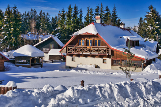 View of snow laden cottages nestled amongst the dark green spruces under a crisp blue sky a serene winter scene in Donovaly Banskobystricky kraj Slovakia. View of snow laden cottages nestled amongst the dark green spruces under a crisp blue sky a serene winter scene in Donovaly Banskobystricky kraj Slovakia.
