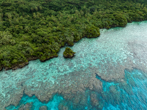 Aerial view of vibrant turquoise waters meeting the lush emerald shoreline a serene coastal tableau Hunete Loyalty Islands Province New Caledonia. Aerial view of vibrant turquoise waters meeting the lush emerald shoreline a serene coastal tableau Hunete Loyalty Islands Province New Caledonia.
