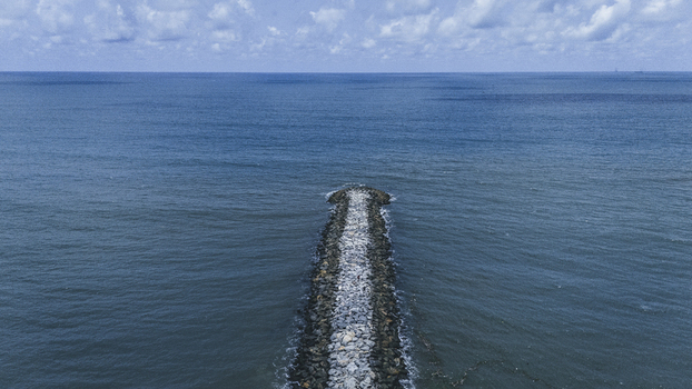 Aerial view of a stone breakwater extending into the deep blue Atlantic Ocean under a cloudy sky near Lekki Beach Road Lekki Lagos Nigeria. Aerial view of a stone breakwater extending into the deep blue Atlantic Ocean under a cloudy sky near Lekki Beach Road Lekki Lagos Nigeria.