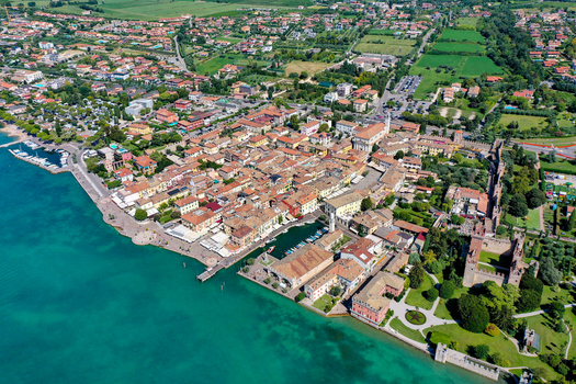 Aerial view of the historic town of Lazise featuring the Scaligero Castle and harbor along the turquoise shores of Lake Garda Lazise Veneto Italy.