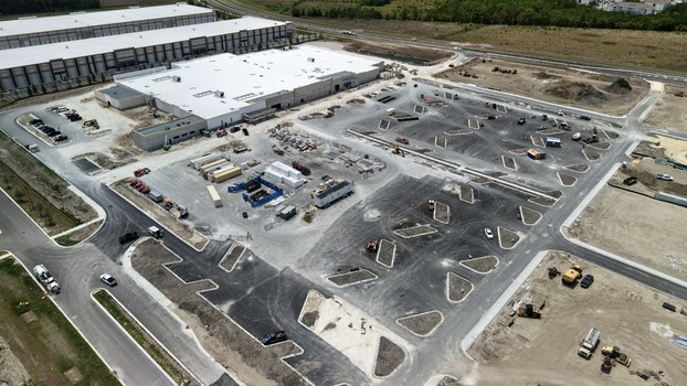 Aerial view of Foundry Lane construction site featuring large industrial warehouses and a developing parking lot with heavy machinery in World Golf Village Florida United States.
