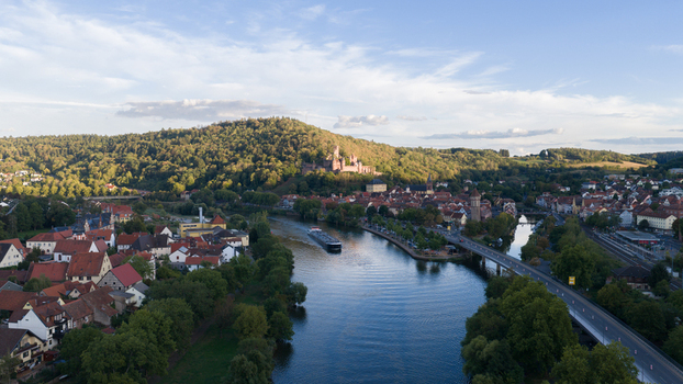 Aerial view of Wertheim Castle overlooking the historic town and the Main river with a cargo ship passing by in Wertheim Baden Wurttemberg Germany.